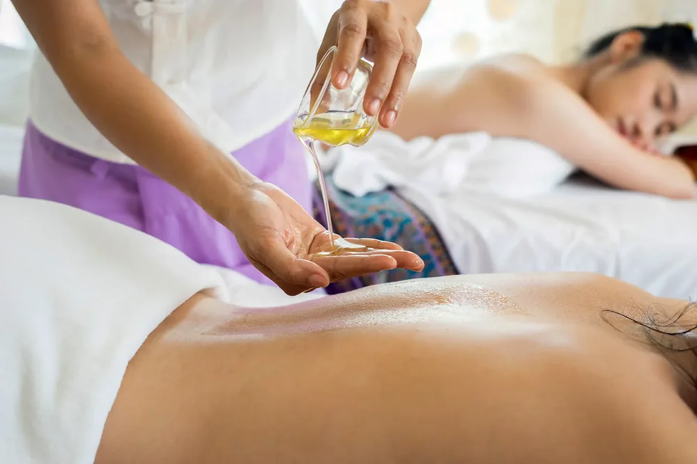 Huile de massage versée au creux de la main pendant un soin